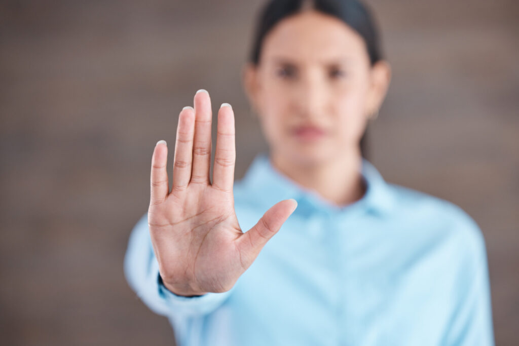 Gros plan de la main d'une femme d'affaires métisse faisant un geste d'arrêt dans son bureau. Stop au sexisme, à l'inégalité et au harcèlement sexuel sur le lieu de travail.